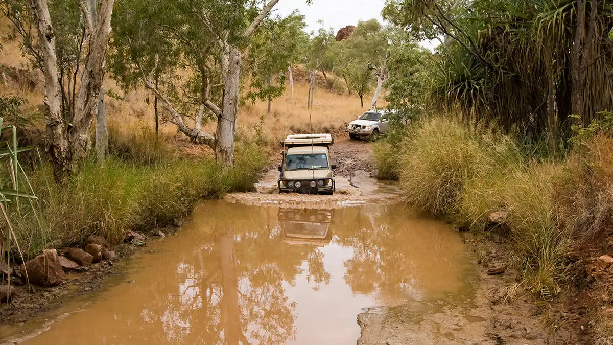 4WD vehicles driving through muddy water in a remote off-grid location, representing GPS fleet tracking solutions for construction, mining, and rugged environments."