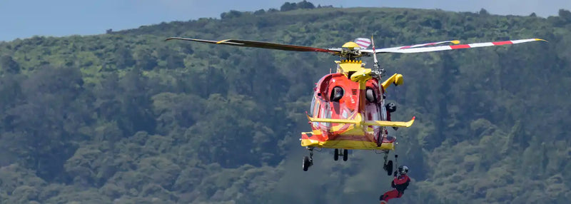 Rescue helicopter lifting a person in a remote area, representing off-grid GPS and satellite tracking solutions for vehicles, equipment, and personnel across Australia’s Outback, mines, farms, marine, and adventure travel.